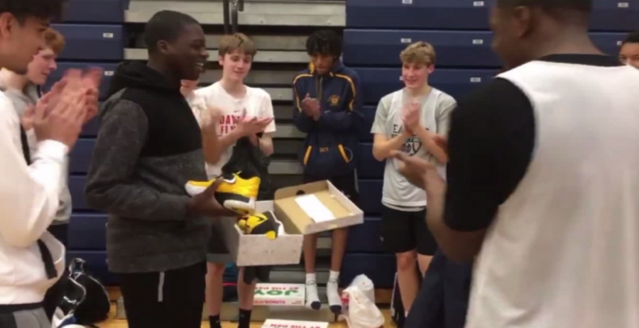 Team manager SENIOR David Akanbi is seen surrounded by his teammates after being presented with his gift from the team. Max Poynter, ‘22, had the idea to raise money for the new shoes.