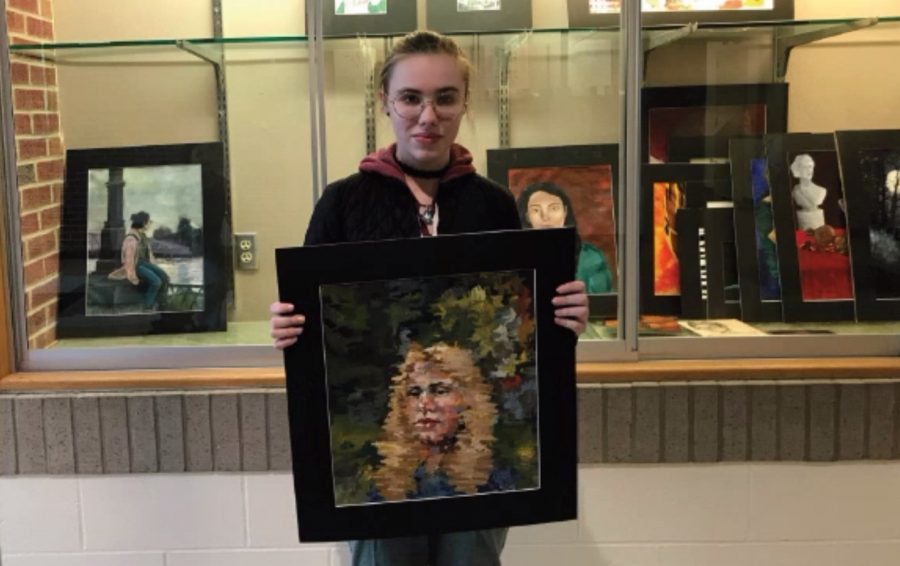 Alexandra Franz, ‘23, poses with her favorite piece from the Scholastic Art Awards. Franz received 19 awards for her work. 
