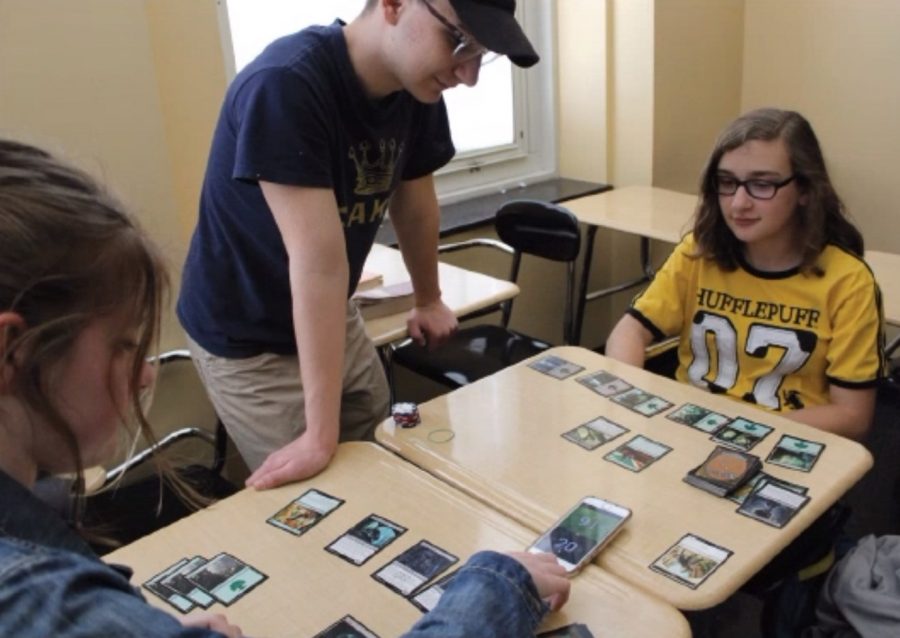 From left to right: Megan Graeler, ‘21, Lincoln Messerly, ‘21 and Sofia Moliterno, ‘23, play a card game after school as a part of the tabletop game club. Just like the unique mixing of grades in the tabletop game club, students involved in the Eagle Buddies program will be paired with someone from another grade level who will help them with their academic and social life.