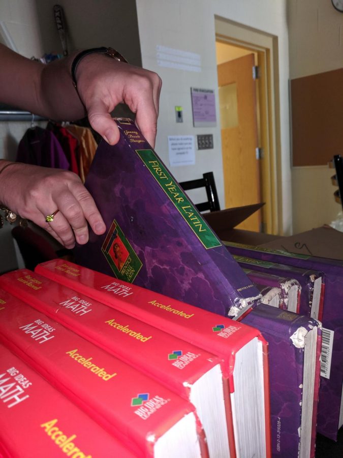 A student lifts a Latin textbook off of a shelf. Although many at WHHS lament the three-year Latin requirement, club writer, Otto Kindel, argues that it is a valuable aspect of WHHS Classical education.