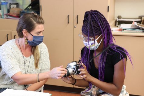Photography teacher Elizabeth Knodle teaches Serentiy Billups ‘24 the basics of photography to start the year off. Knodle is excited to watch her students develop their very first roll of film in the weeks to come. (Hajra Munir)