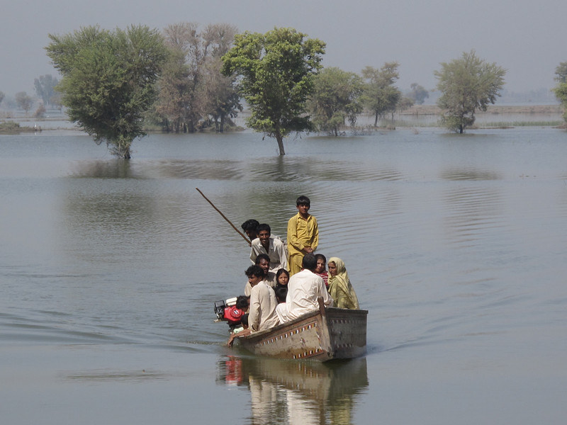 Multiple family members cram together in a small motor boat, trying to escape the floods. 