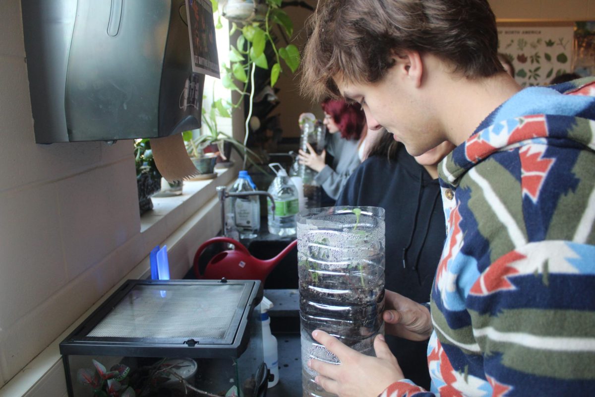 George Wirtz, ‘25, admires the growth of the plants inside of his eco-column project during his environmental science class.