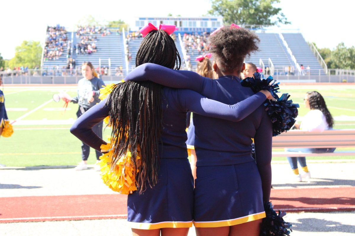 Two+cheerleaders+are+hugging+waiting+for+the+junior+high+pep+rally+to+start.