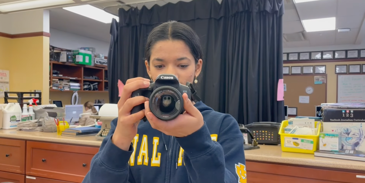 A journalism student holds up a camera. 