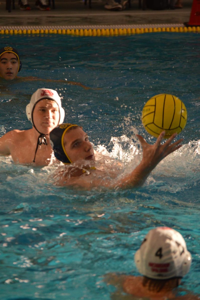 Ernie Manders, '26, grasps the water polo ball during a match.