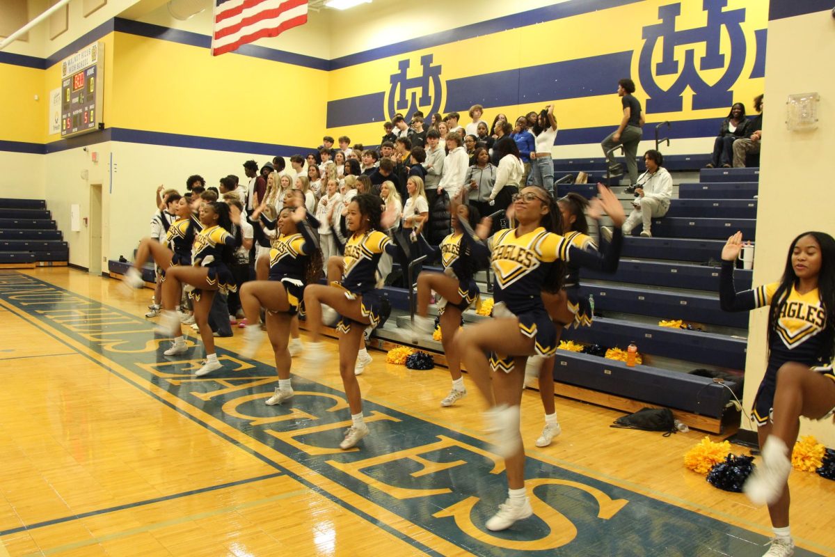 The varsity cheerleading team cheers for the mens varsity basketball game against Oak Hills.